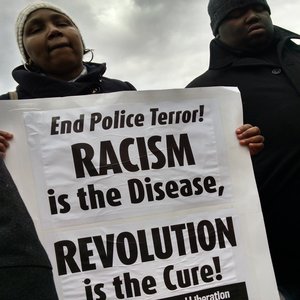 Woman holding Racism is the Disease Revolution is the Cure End Police Terror PSL sign